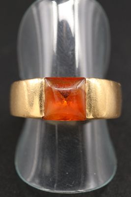 un gros plan d'une bague en or sertie d'une pierre orange