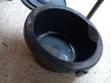 a black toilet bowl sitting on the floor next to a trash can