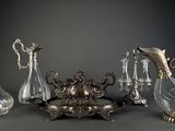 cinq vases en verre et un plat en argent posés sur une table