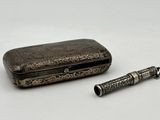 une boîte argentée sur laquelle est représenté un stylo et qui contient un stylo