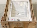 une caisse posée par terre, avec un lavabo à l'intérieur