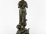 a bronze statue of a woman holding a bird on a rock