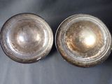 pair of silver plated bowls on a table with a black background