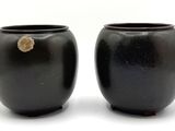 une paire de vases noirs sur fond blanc, avec un petit morceau de roche au milieu