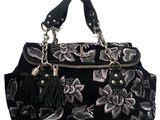sac à main noir et argenté orné de fleurs et de pompons sur fond blanc