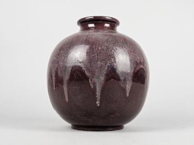 un vase violet posé sur une surface blanche