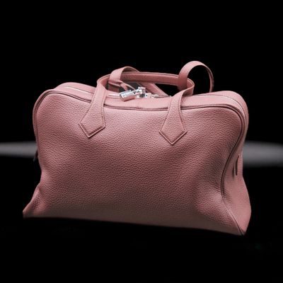 a picture of a pink leather bag on a black background