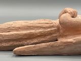 a clay figurine of a frog on a gray surface