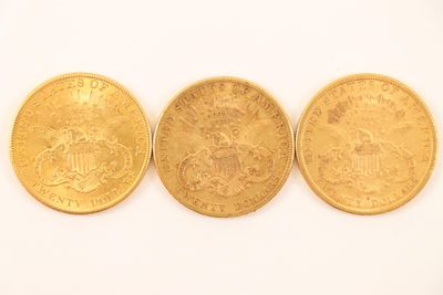 three gold coins are sitting side by side on a white surface