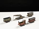 cinq petits trains miniatures posés sur une surface blanche, sur fond noir