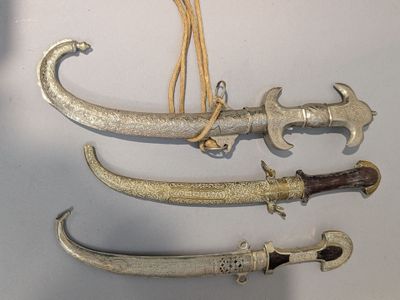 trois types d'armes différents exposés sur une surface blanche