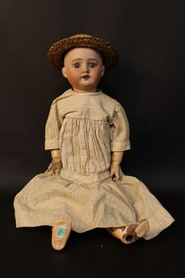 an old doll sitting on a black surface wearing a hat and dress
