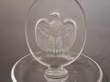a glass bowl with an eagle on it on a plate