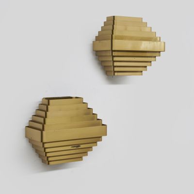 une paire d'appliques en laiton sur un mur blanc