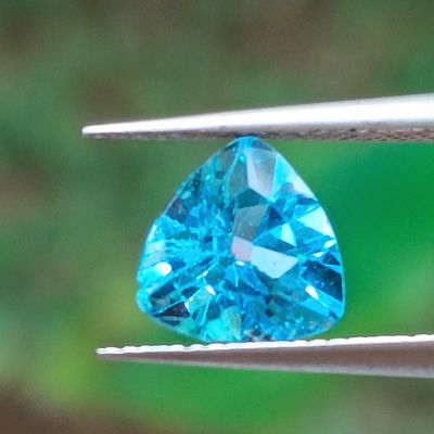 a blue topazt stone being held by a pair of pliers