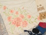 a white blanket with pink roses on it next to a pair of shoes and a hat