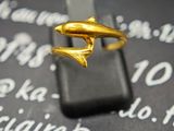une bague en or ornée d'un dauphin, posée sur un téléphone portable