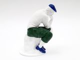 figurine of a man sitting on a toilet with his hands on his knees