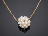 a white pearl and gold necklace on a black surface