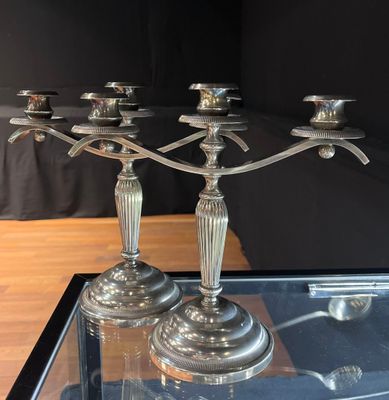 three silver candles on a glass table with a black background