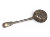 silver spoon and spoon rest on a white surface with a white background