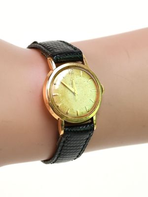 le poignet d'une femme, sur lequel est posée une montre en or