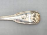 silver spoon with a design on it sitting on a gray surface
