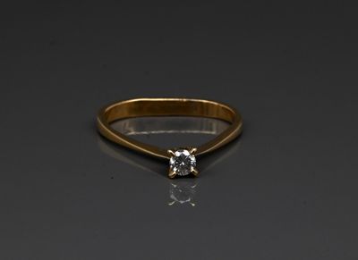 a gold ring with a white diamond on a black surface