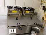 a metal counter with three burners and a bucket on it