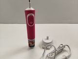 une brosse à dents rose posée sur une table à côté d'un chargeur