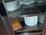 many plates and pans stacked on a shelf in the kitchen