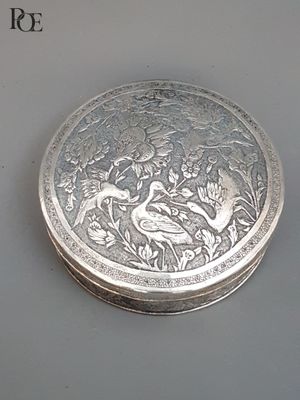 une boîte en argent ornée d'un oiseau, posée sur une table
