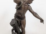 bronze statue of a man holding a torch in his right hand