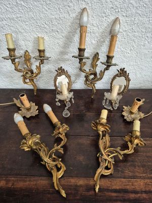 four antique brass wall sconces with candles on a wooden table