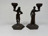 pair of bronze figurines of a woman and a man holding a vase