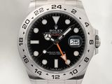 une montre Rolex avec un cadran noir et des aiguilles orange