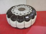 a black and white pouffe sitting on a red surface