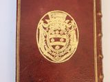 an old book with a gold emblem on it sitting on a white surface