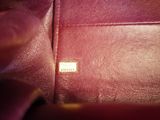 someone is holding a purple purse with a small tag on it