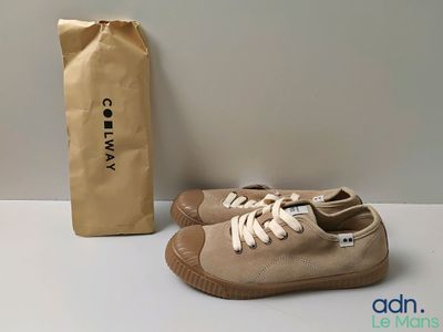 coles tan canvas sneakers and a brown paper bag on a table