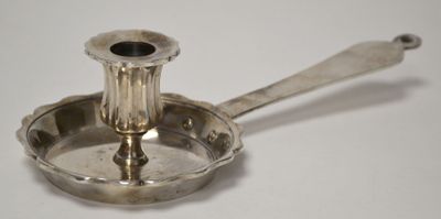 un petit bougeoir en argent posé sur une table blanche