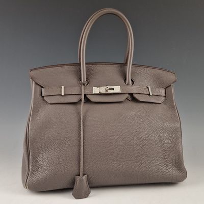 un sac à main en cuir gris muni d'un fermoir métallique sur la poignée