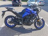 a blue motorcycle parked in a parking lot next to a car