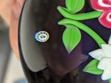a close up of a purple vase with flowers and a ladybug on it