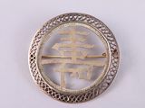 an image of a silver brooch with a chinese symbol on it
