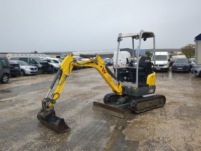 the back end of a small excavator parked in a parking lot