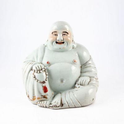 une statue représentant un Bouddha souriant, assis sur une surface blanche