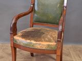 une vieille chaise en bois recouverte de cuir vert, posée sur un parquet