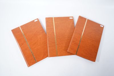 trois cahiers marron posés sur une surface blanche, sur fond blanc