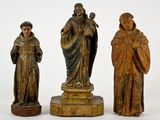 trois statues en bois représentant des hommes et des femmes, sur fond blanc